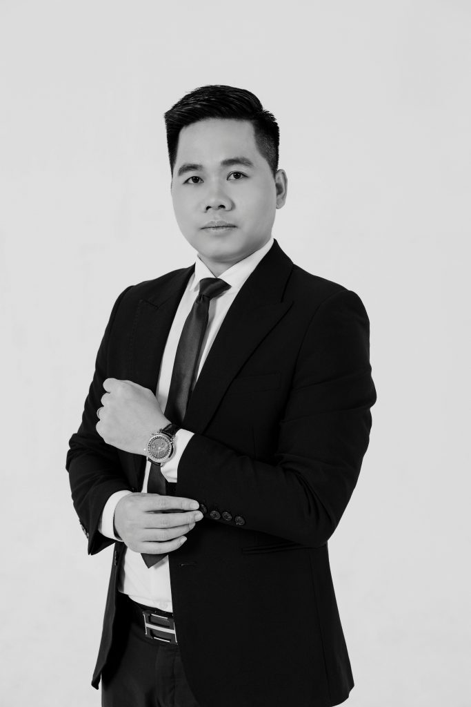 Confident Asian man in a suit posing in a studio setting, black and white photo.